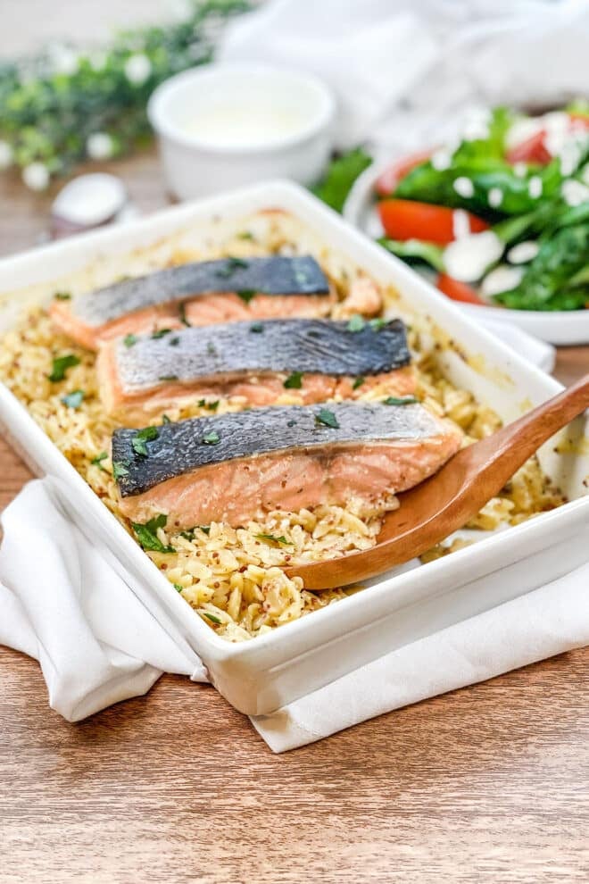 White rectangular dish with orzo and salmon fillets.