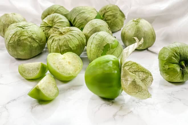 Tomatillos, some with husks removed, one cut open.