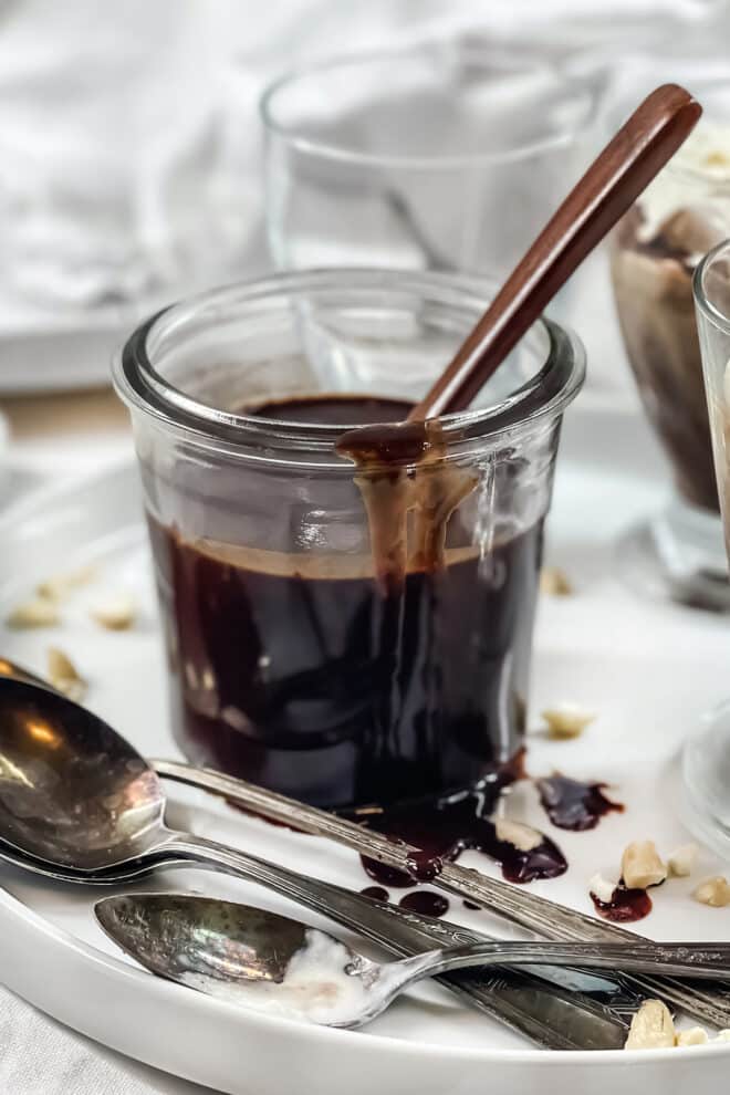 Glass jar with chocolate sauce and spoons.