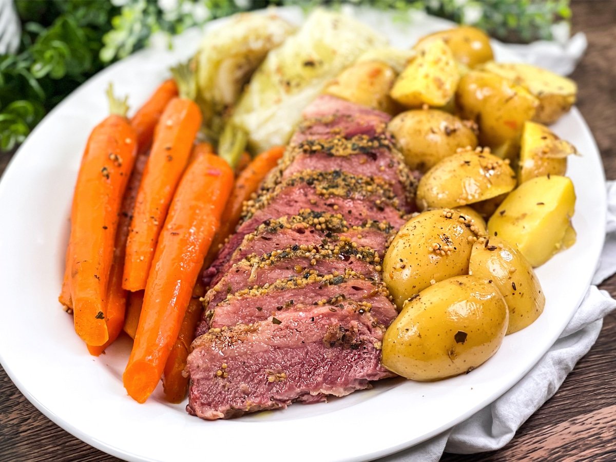 White platter with whole carrots, corned beef, cabbage ,and baby potatoes.