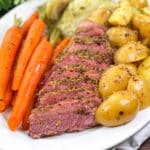 White platter with whole carrots, corned beef, cabbage ,and baby potatoes.
