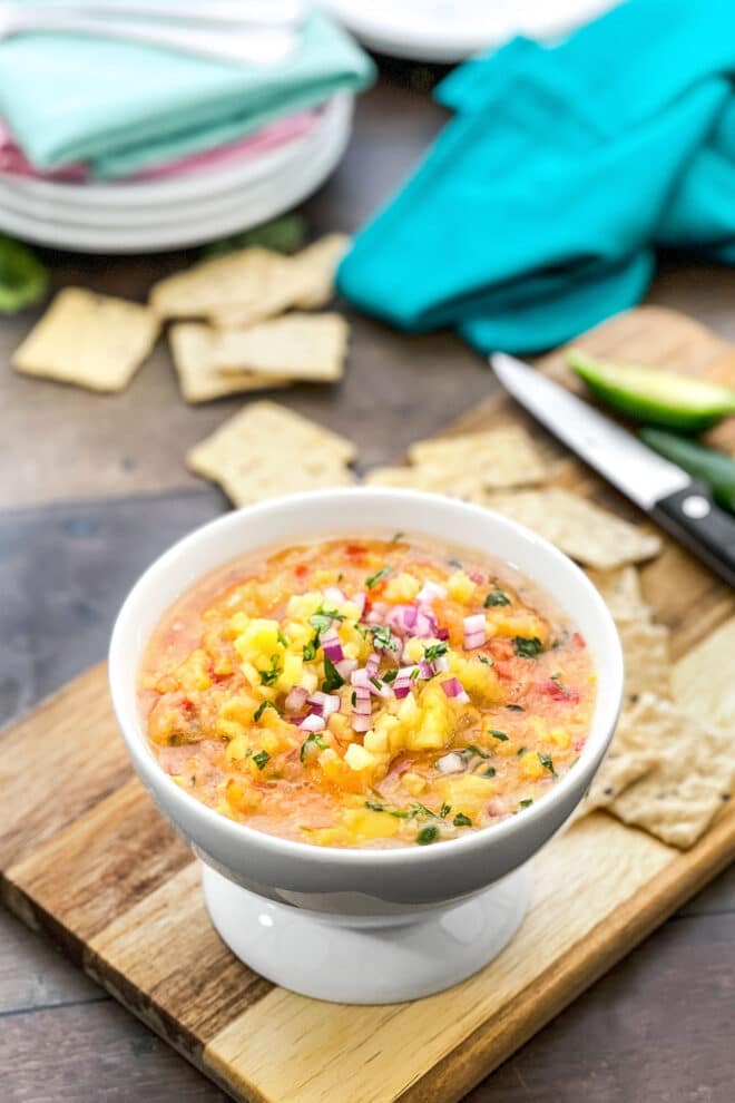 Tropical mango salsa in a white bowl with crackers in background.