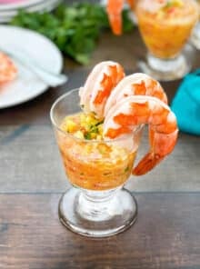 Glass with tropical cocktail sauce and shrimp hanging off the side.