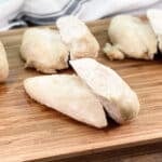 several chicken breasts on a wooden cutting board