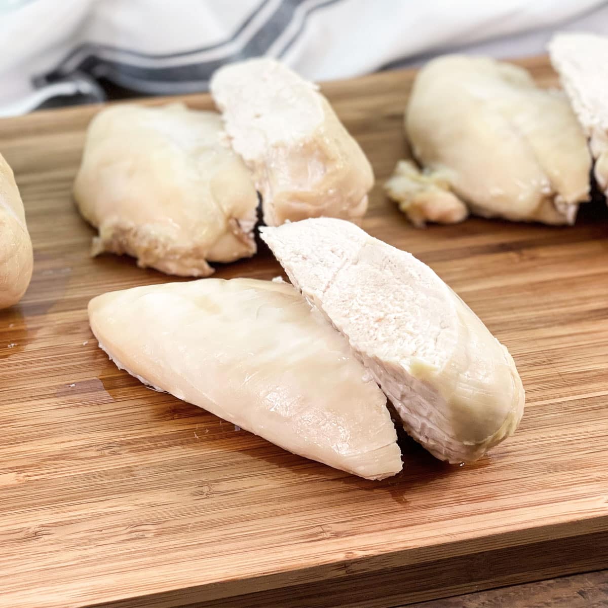 several chicken breasts on a wooden cutting board