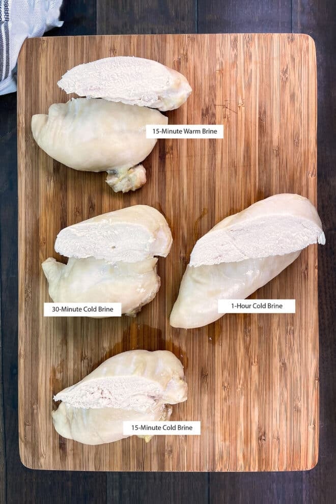 4 halved chicken breasts on a wooden cutting board with labels stating how long each was brined for.