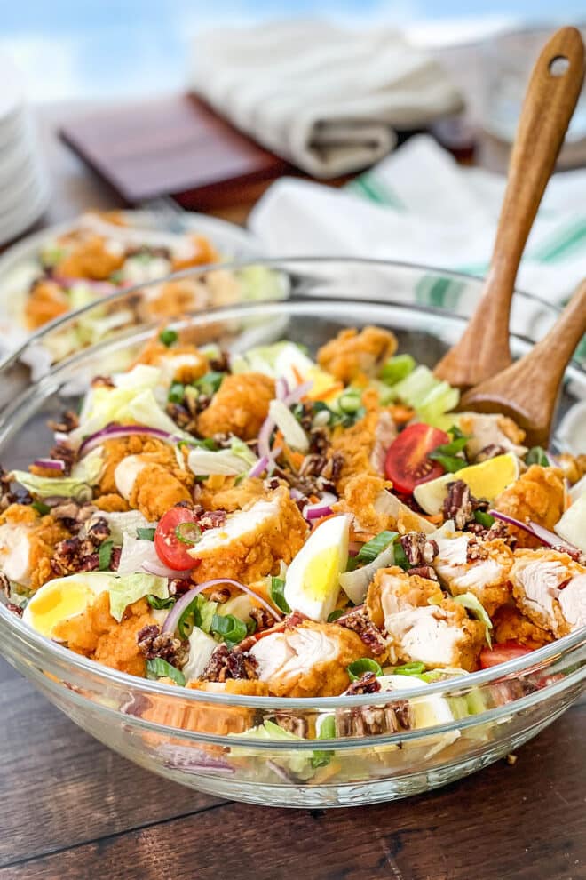 Large glass bowl of salad with chopped hard-boiled eggs and chicken tenders. 