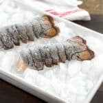 Two frozen lobster tails on ice.