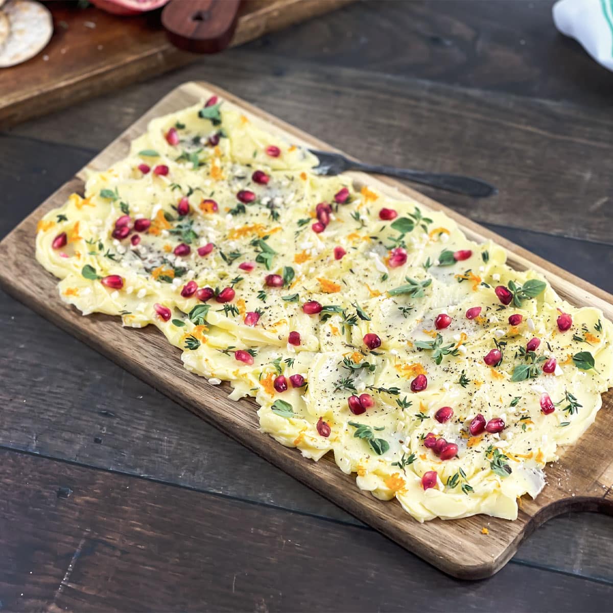 Rectangular butter board with pomegranate seeds and herbs