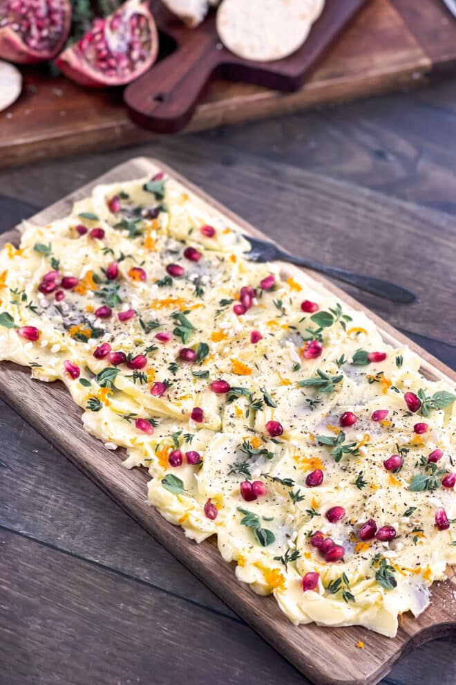 Rectangular butter board with pomegranate seeds and herbs