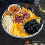 Halloween Charcuterie Board with cheese, meat, dark grapes, dried apricots, and crackers.
