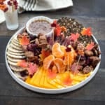 Thanksgiving charcuterie board with meat, cheese, crackers, orange segments, and candied nuts.