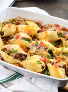Taco Stuffed Shells topped with cheese, green onion, and tomato.