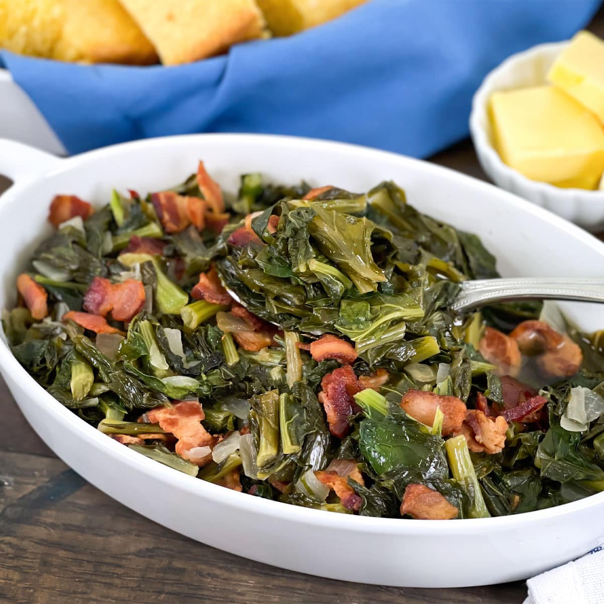 Southern turnip greens with bacon in shallow white serving bowl.