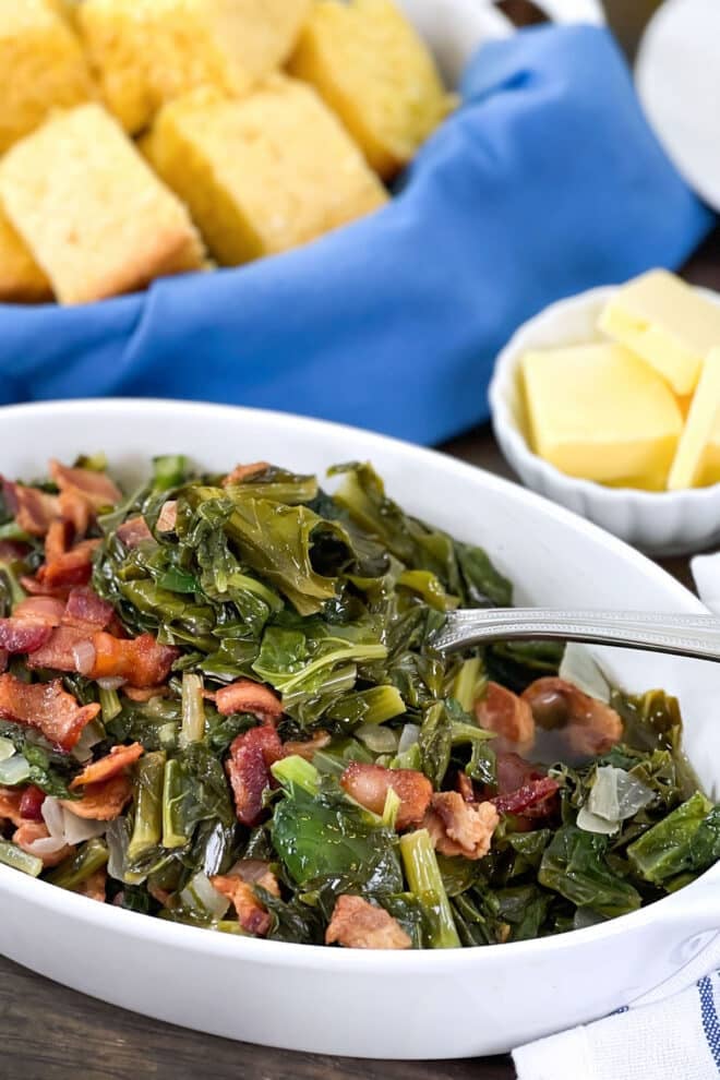 Southern turnip greens with bacon in shallow white serving bowl.