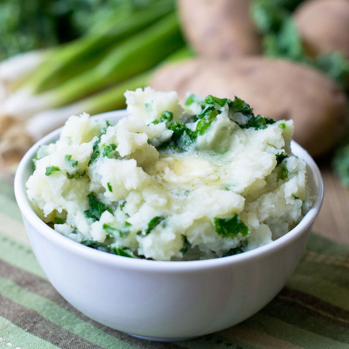 A bowl of Irish Colcannon (mashed potatoes mixed with wilted kale, topped with butter that is melting on top
