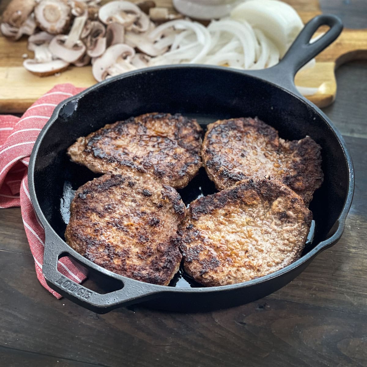 Four cooked cube steaks in a cast iron pan.