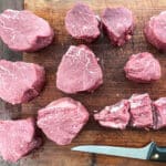 Beef tenderloin cut into steaks on a cutting board.