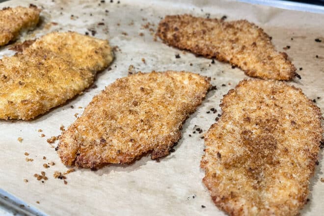 Baked and breaded chicken cutlets on parchment.