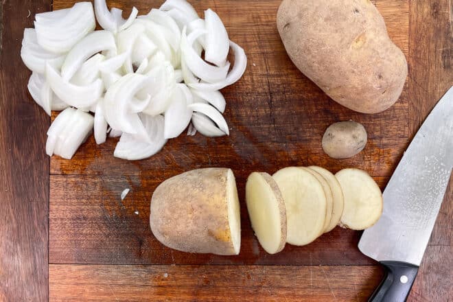 Russet potatoes and vidalia onions being cut into 1/4 inch slices.