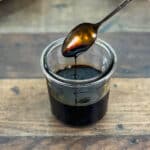 Spoon dripping over glass jar of browning sauce.