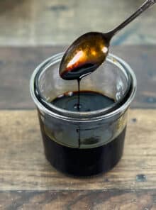 Spoon dripping over glass jar of browning sauce.