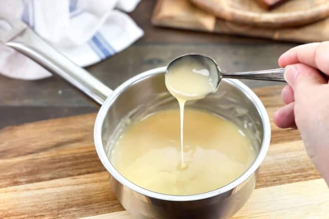 Velouté Sauce dripping from a spoon over a saucepan of veloute.