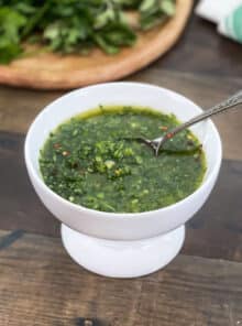 Fresh chimichurri sauce in a white bowl with spoon.