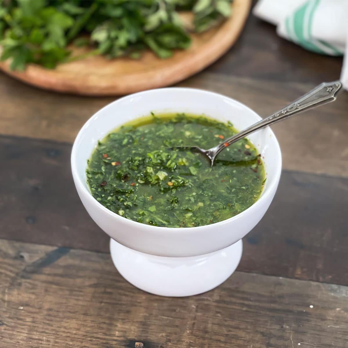 Fresh chimichurri sauce in a white bowl with spoon.