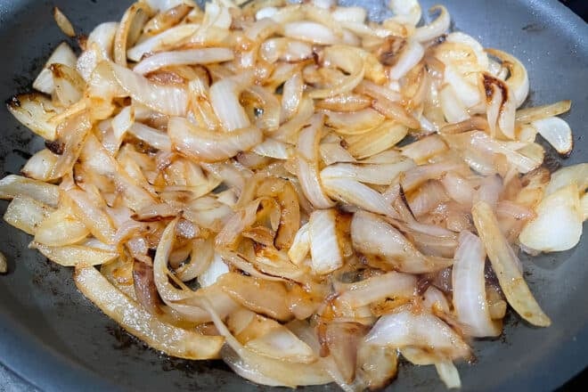 Skillet of browning onion slices in the process of making onion gravy.