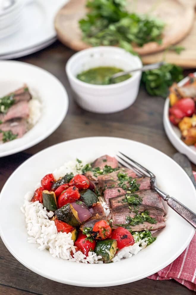 Rice bowl with sauteed vegetables and sliced steak with chimichurri sauce.