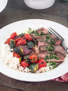 Rice bowl with sauteed vegetables and sliced steak with chimichurri sauce.