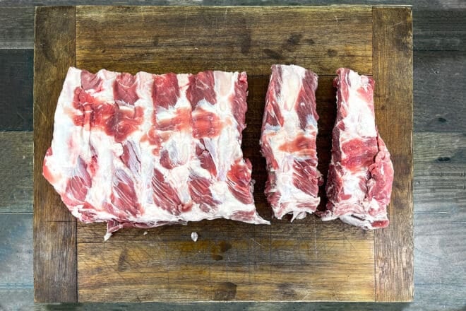 Raw beef ribs on a wooden cutting board.