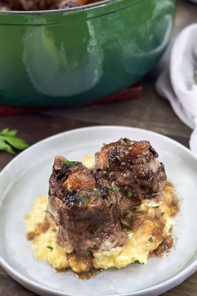 Braised oxtails over mashed potatoes on a plate.