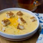 Bowl of beer cheese soup with croutons and shredded cheese on top.