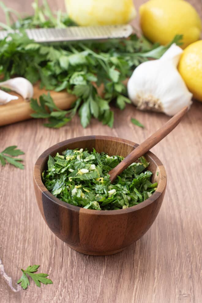 Fresh gremolata in a wooden spoon with wooden spoon.