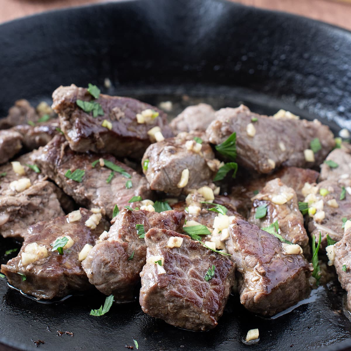 Steak Tips with garlic butter in a cast iron skillet.