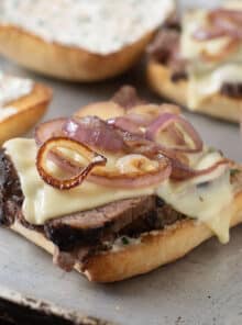 Tri-tip sandwich on a ciabatta roll with melty cheese and browned red onion slices.