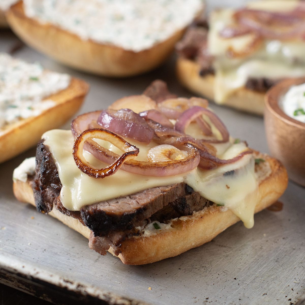 Tri-tip sandwich on a ciabatta roll with melty cheese and browned red onion slices.