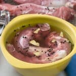 Pork tenderloin in wet brine in yellow bowl, tenderloins dry brining in background.
