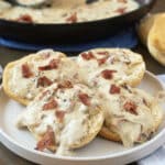 Creamy bacon gravy over biscuits on a plate.