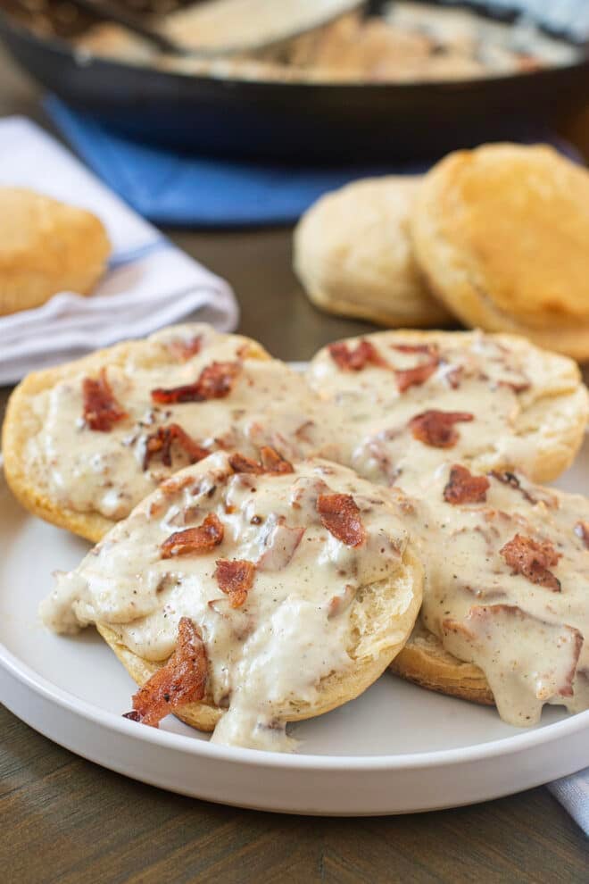 Creamy bacon gravy over biscuits on a plate.