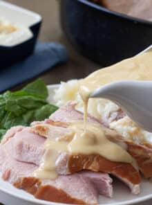 Ham gravy being poured over slices of baked ham.