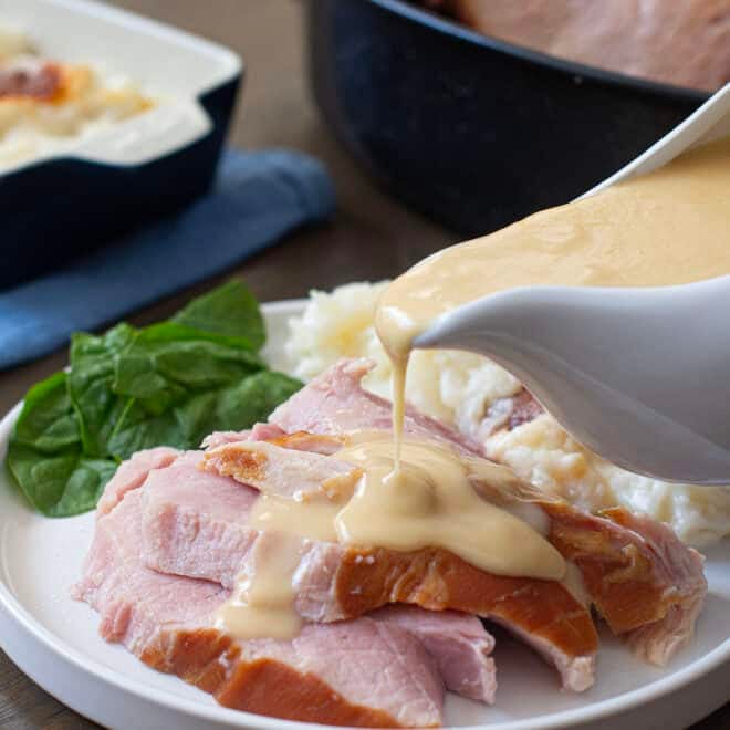 Ham gravy being poured over slices of baked ham.