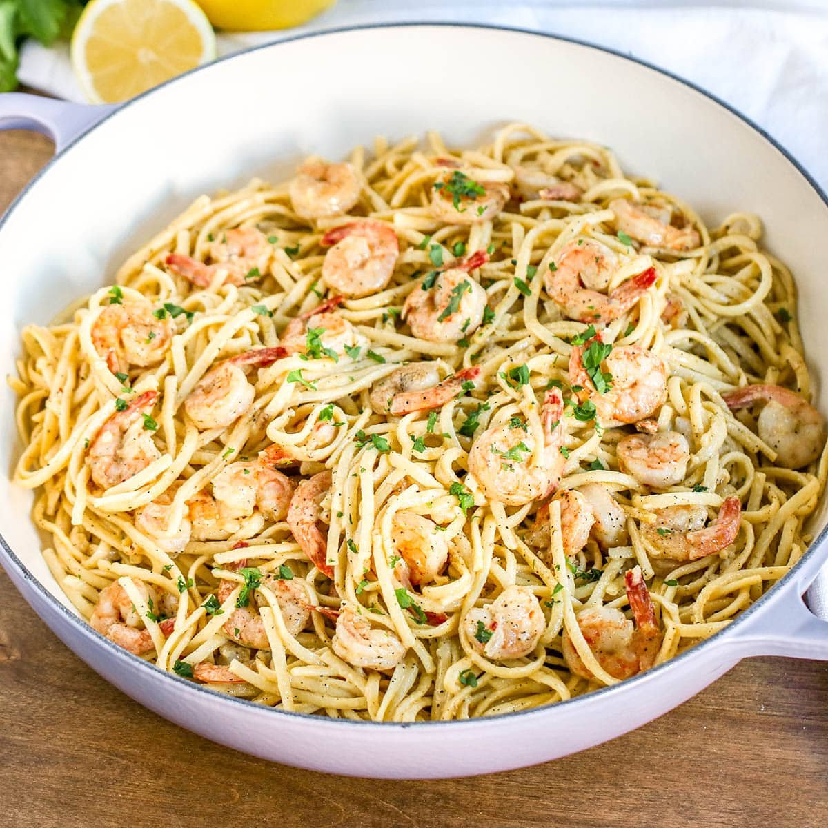 Shrimp pasta dish with fresh parsley on top in large white pot.