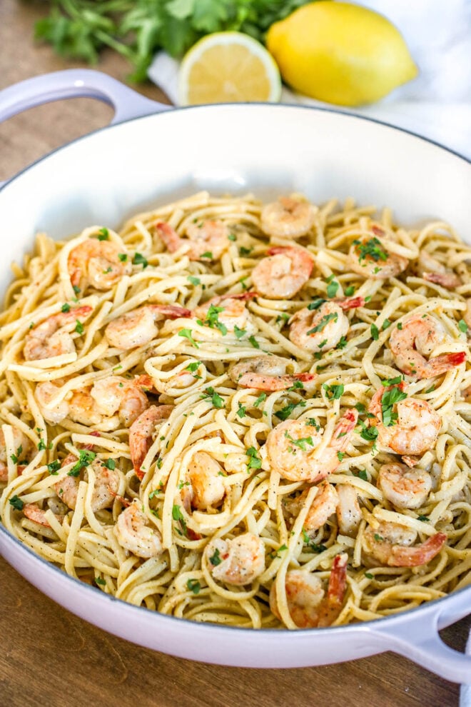 Shrimp pasta dish with fresh parsley on top in large white pot.