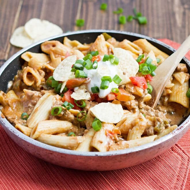 Taco Pasta in a large skillet topped with sour cream and green onion.