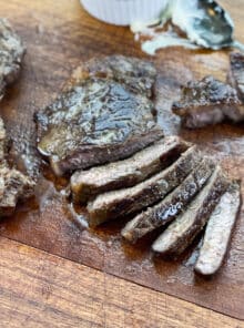 Sliced, well-done steaks on a cutting board with steak butter.