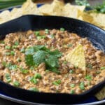 Creamy Sausage Dip in a cast iron pan with tortilla chips around.