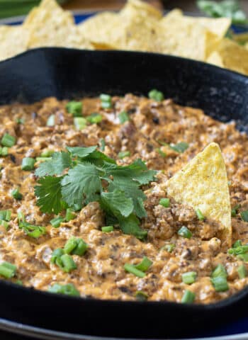 Creamy Sausage Dip in a cast iron pan with tortilla chips around.